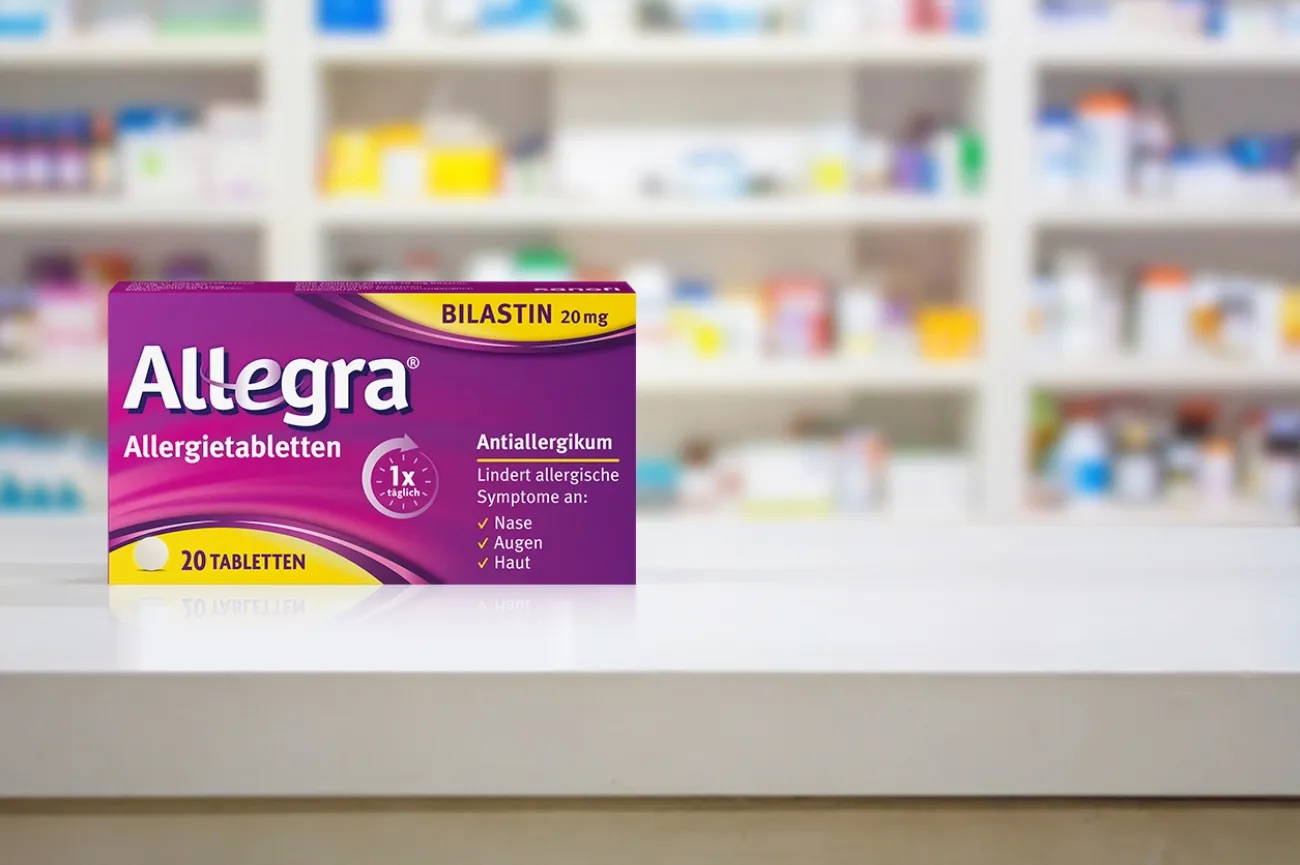 Eine Packung Allegra Allergietabletten vor einem Regal mit anderen Medikamenten