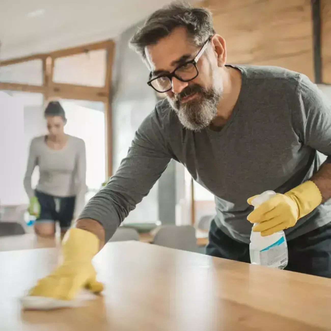 A woman wears gloves while cleaning the inside of her windows