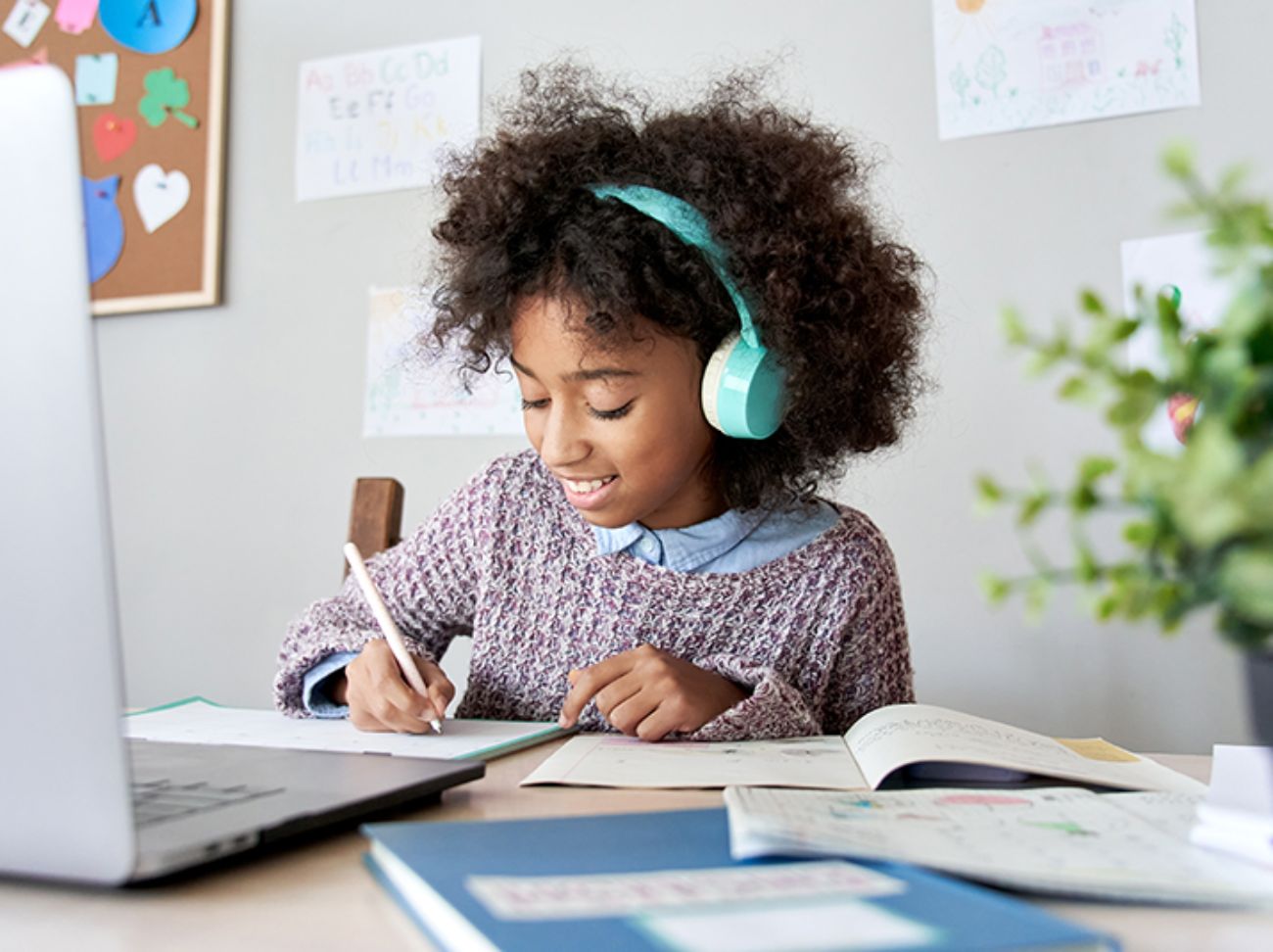 A happy girl wearing headphones and focused on her schoolwork.