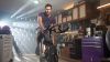 Homme avec chandail violet sur un vélo stationnaire