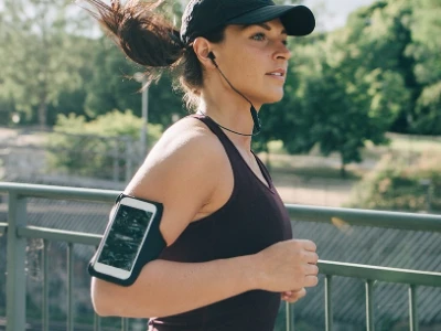 Woman jogging on a bridge on a sunny day, with trees nearby