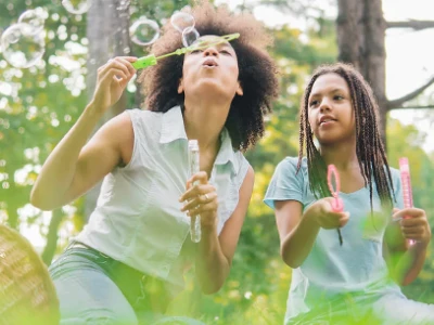 Mom and daughter blowing bubbles in a forest.