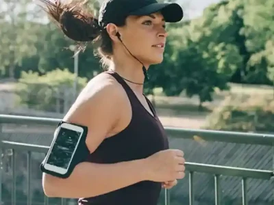 Femme faisant son jogging sur une passerelle pendant une journée ensoleillée, avec des arbres à proximité