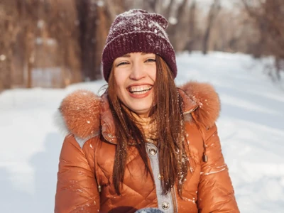 La femme est assise dehors dans la neige et rit.