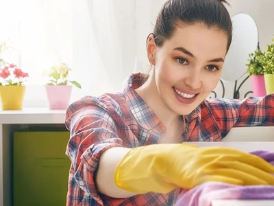 Vrouw poetst de bovenkant van een kast met een paarse poetsdoek