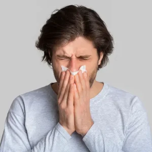  a woman using a tissue to relieve allergy symptoms that affects sleep quality