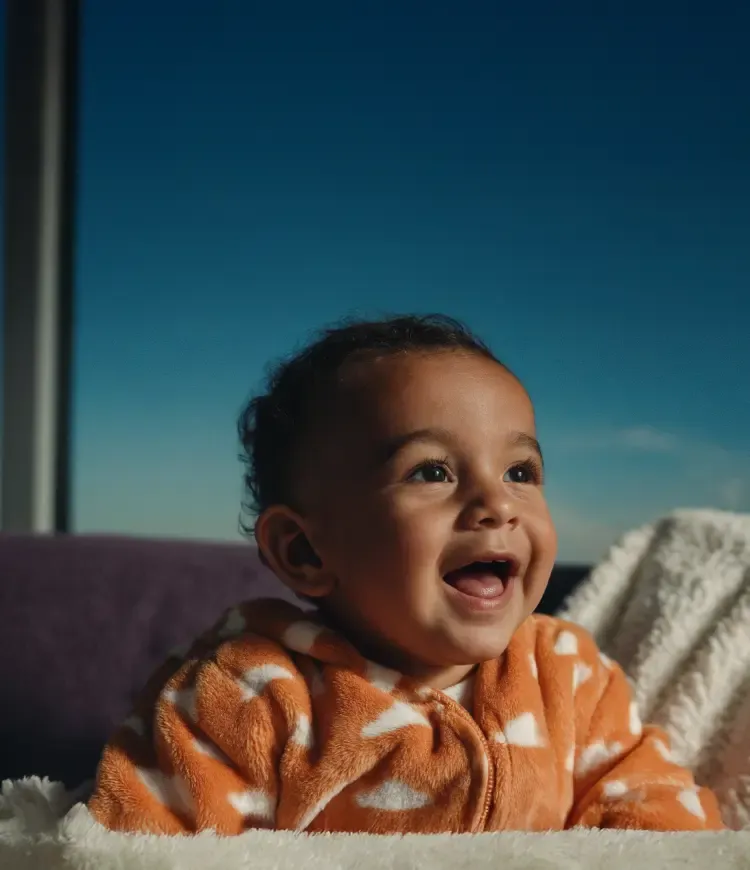 Eine schwangere Frau steht auf einer Blühenden Wiese und hält sich den Bauch.