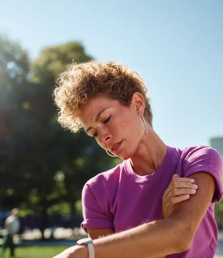 Mulher se olhando no espelho e tocando o próprio rosto