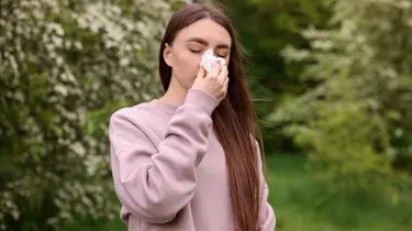 a woman with allergy symptoms in an outdoor setting 