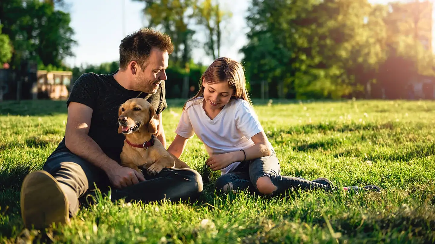 Father with daughter and dog laying on grass