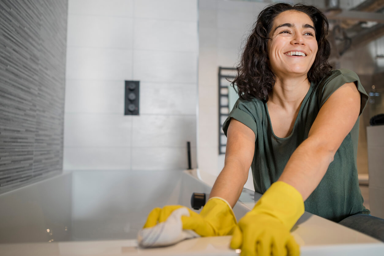 Eine Frau wischt mit einem Tuch über den Rand ihrer Badewanne.