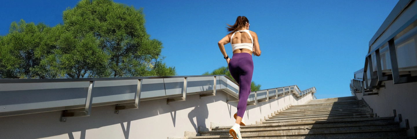 Active woman dressed in sportswear climbing stairs outdoors