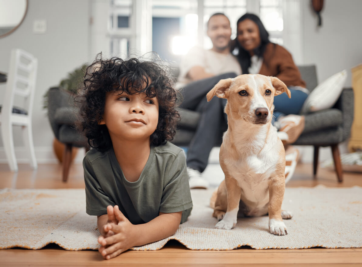 Kleiner Junge liegt neben seinem Hund auf dem Boden.