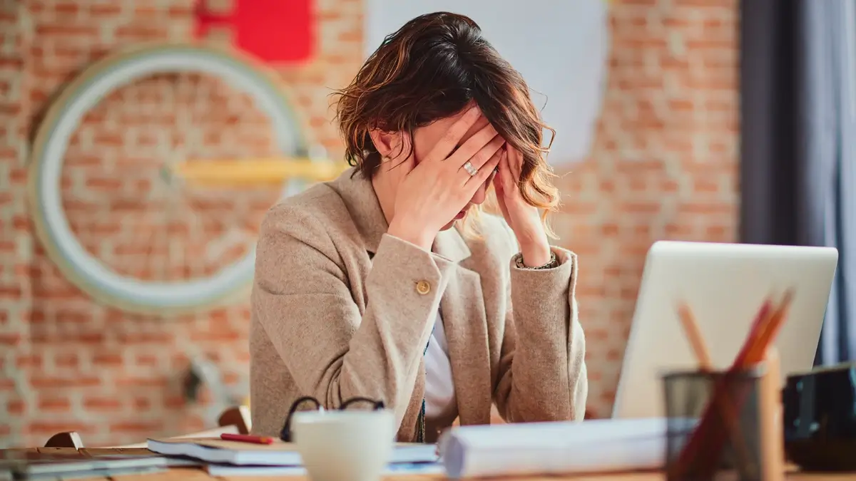 Une femme à son bureau se sentant extrêmement stressée.