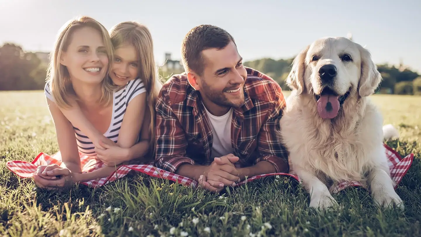 Jong gezin ligt op het gras samen met hun hond te genieten van de zonnige weer.