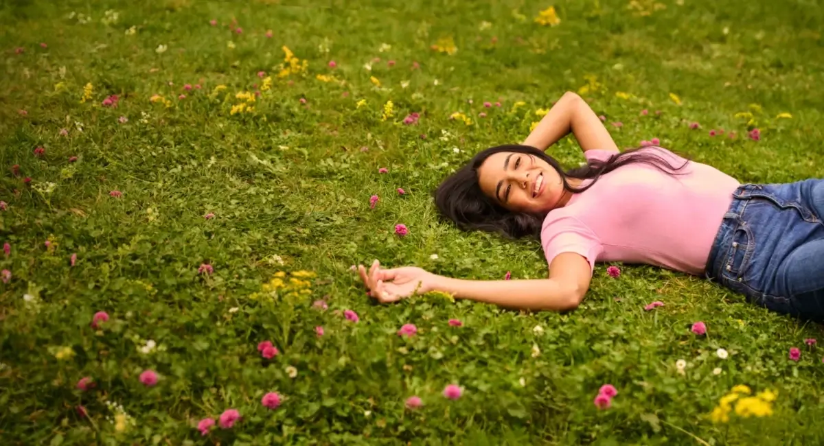 Une femme debout en toute confiance à l'extérieur devant des arbres.