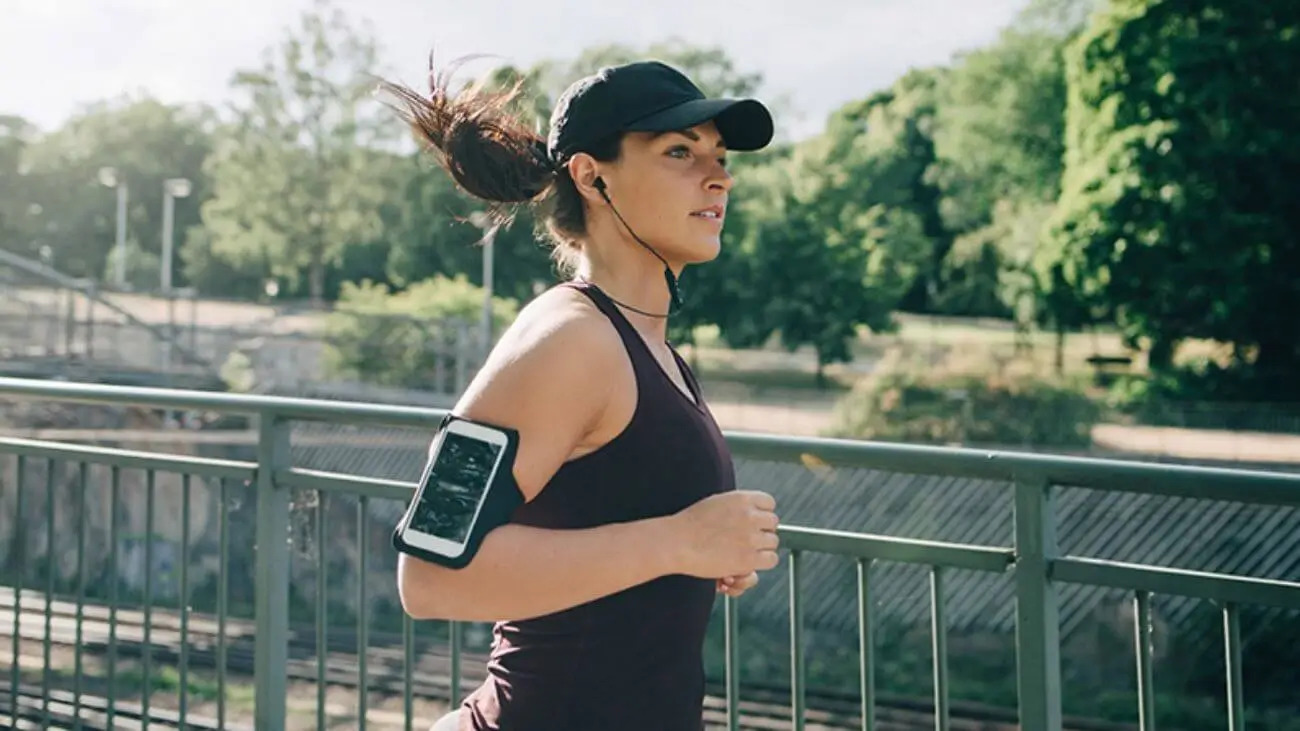 Woman jogging on a bridge on a sunny day, with trees nearby